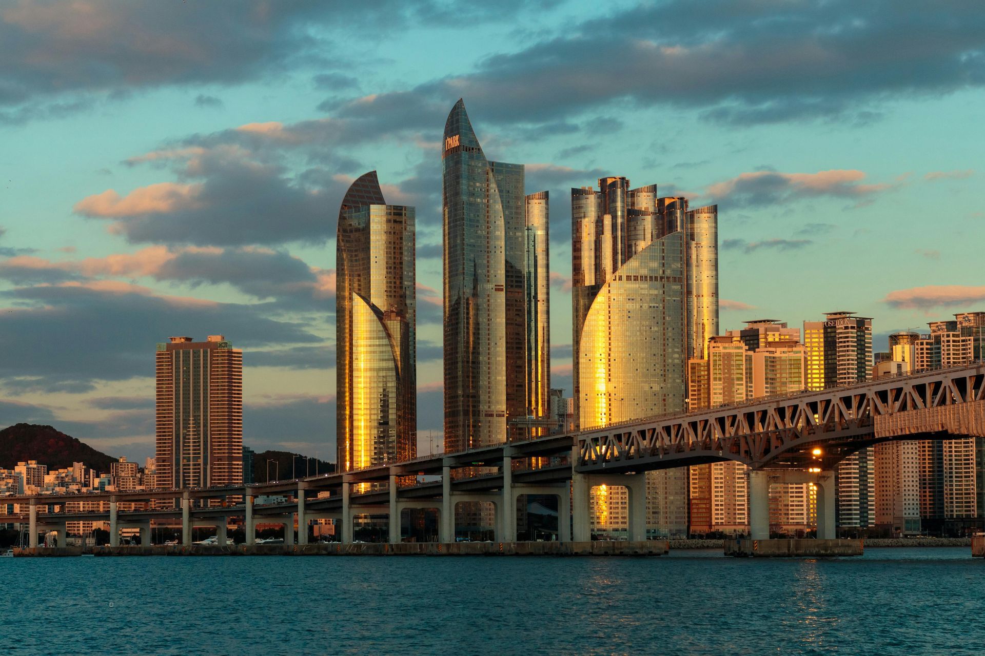 Sunset skyline of modern glass skyscrapers beside a bridge over blue water