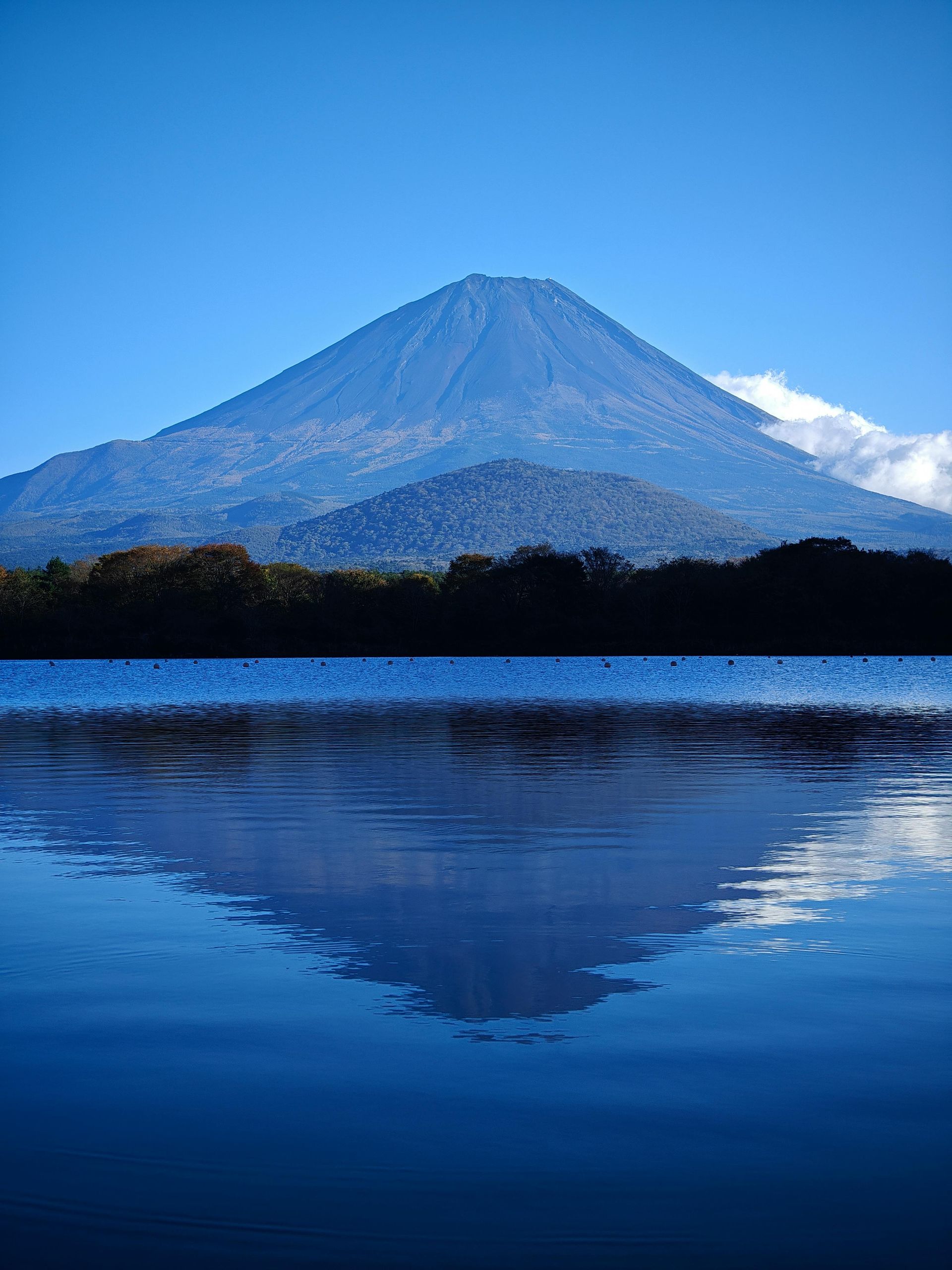 Mountain reflected in calm lake under a clear, blue sky. Hakone