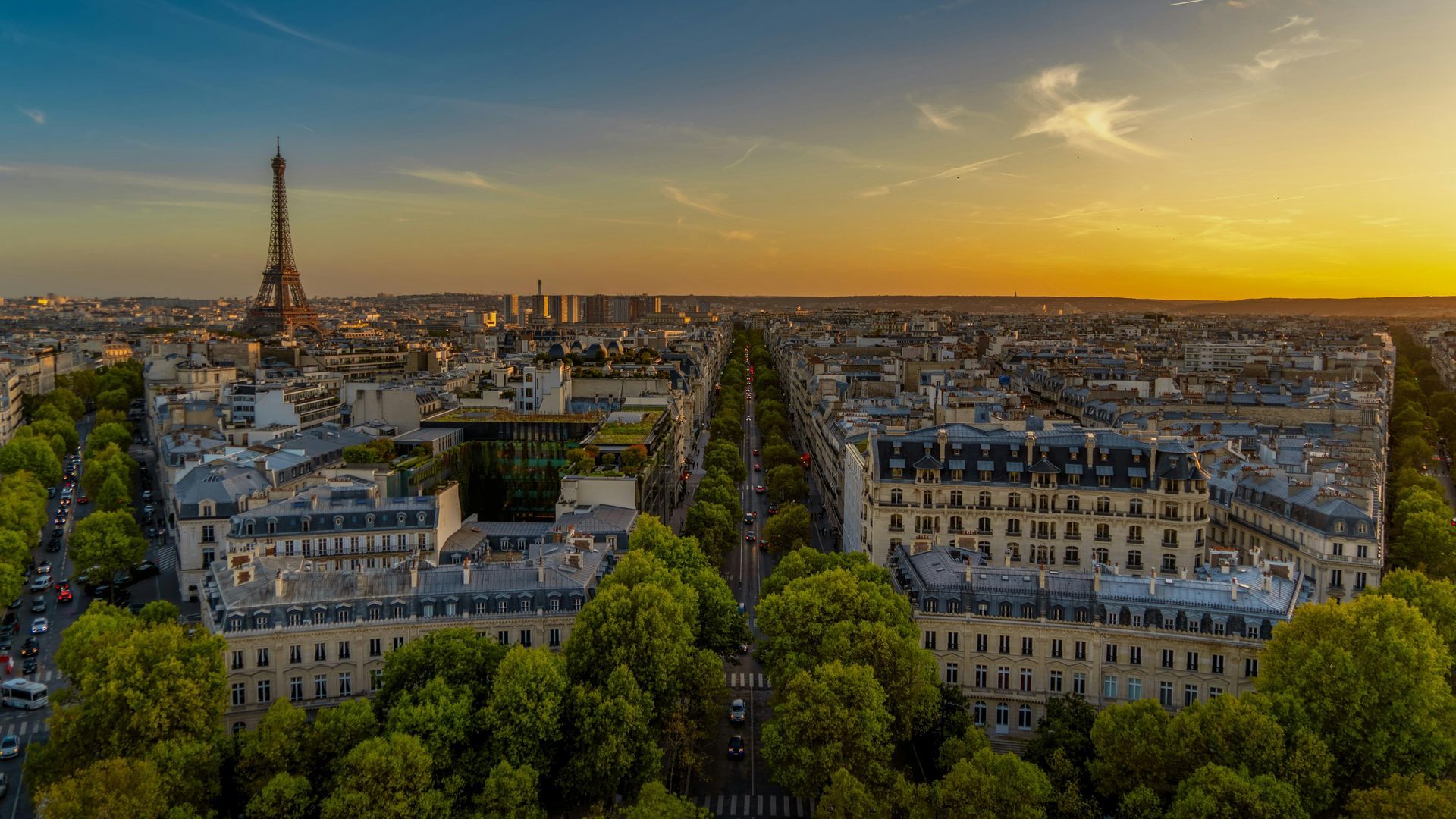 Paris skyline at sunset, featuring the Eiffel Tower, tree-lined boulevards, and classic architecture.