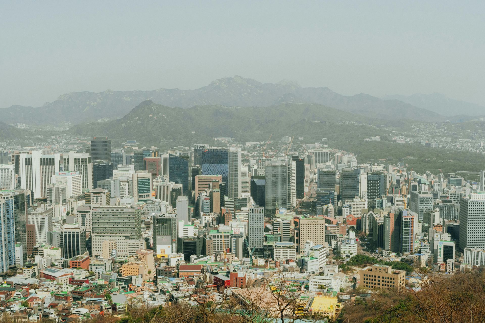 City skyline with dense high-rises under hazy mountains in the background