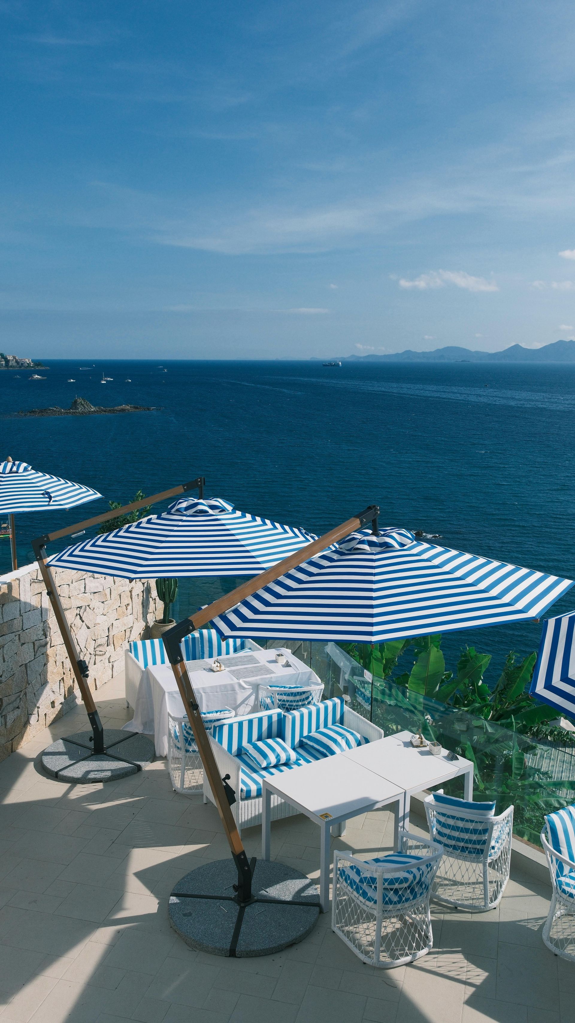 Outdoor restaurant overlooking the ocean with blue and white striped umbrellas, tables, and chairs. Cannes French Riviera