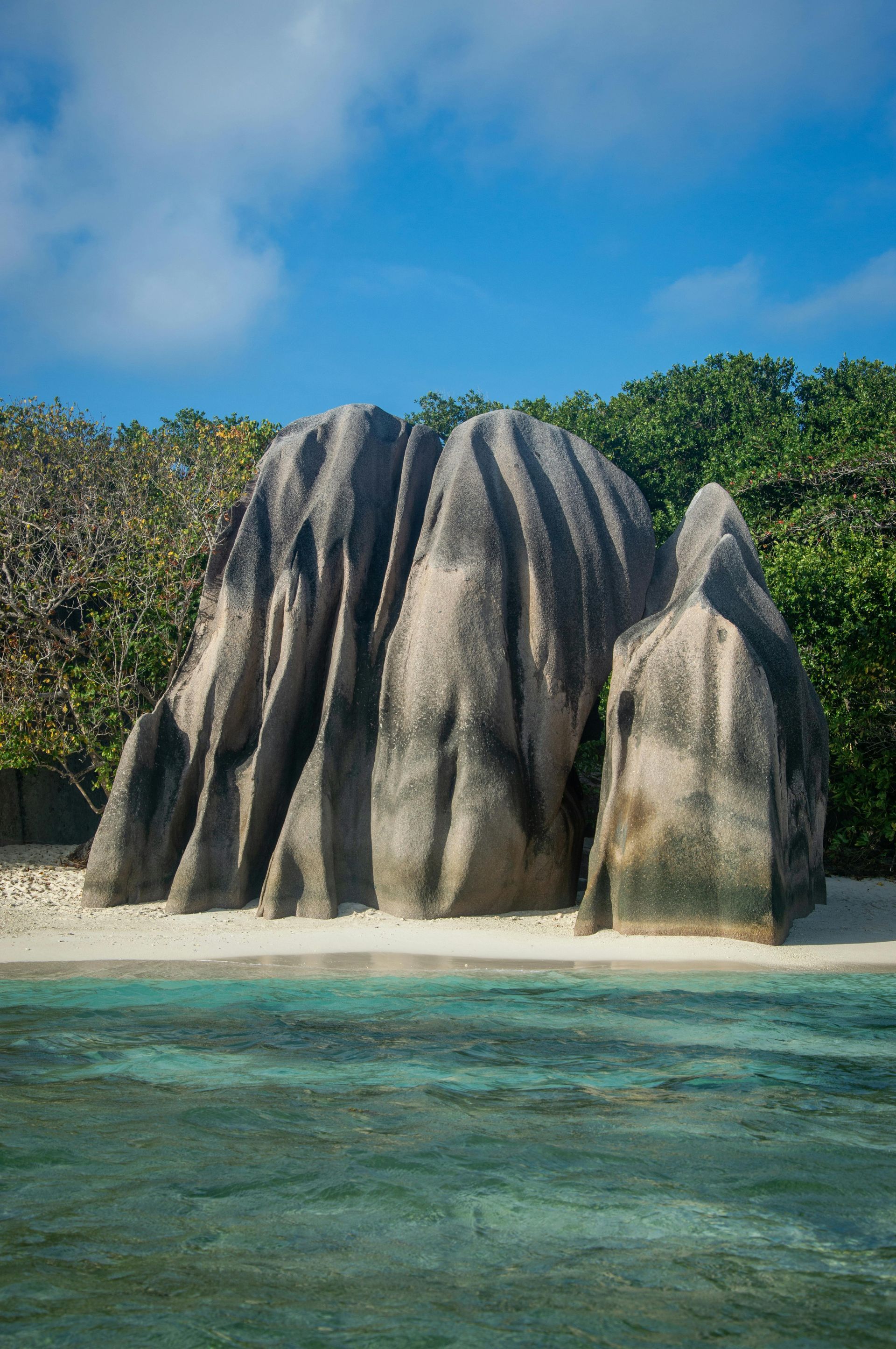 Large granite rock formations on a white sand beach with turquoise water, La Digue, Seychelles.