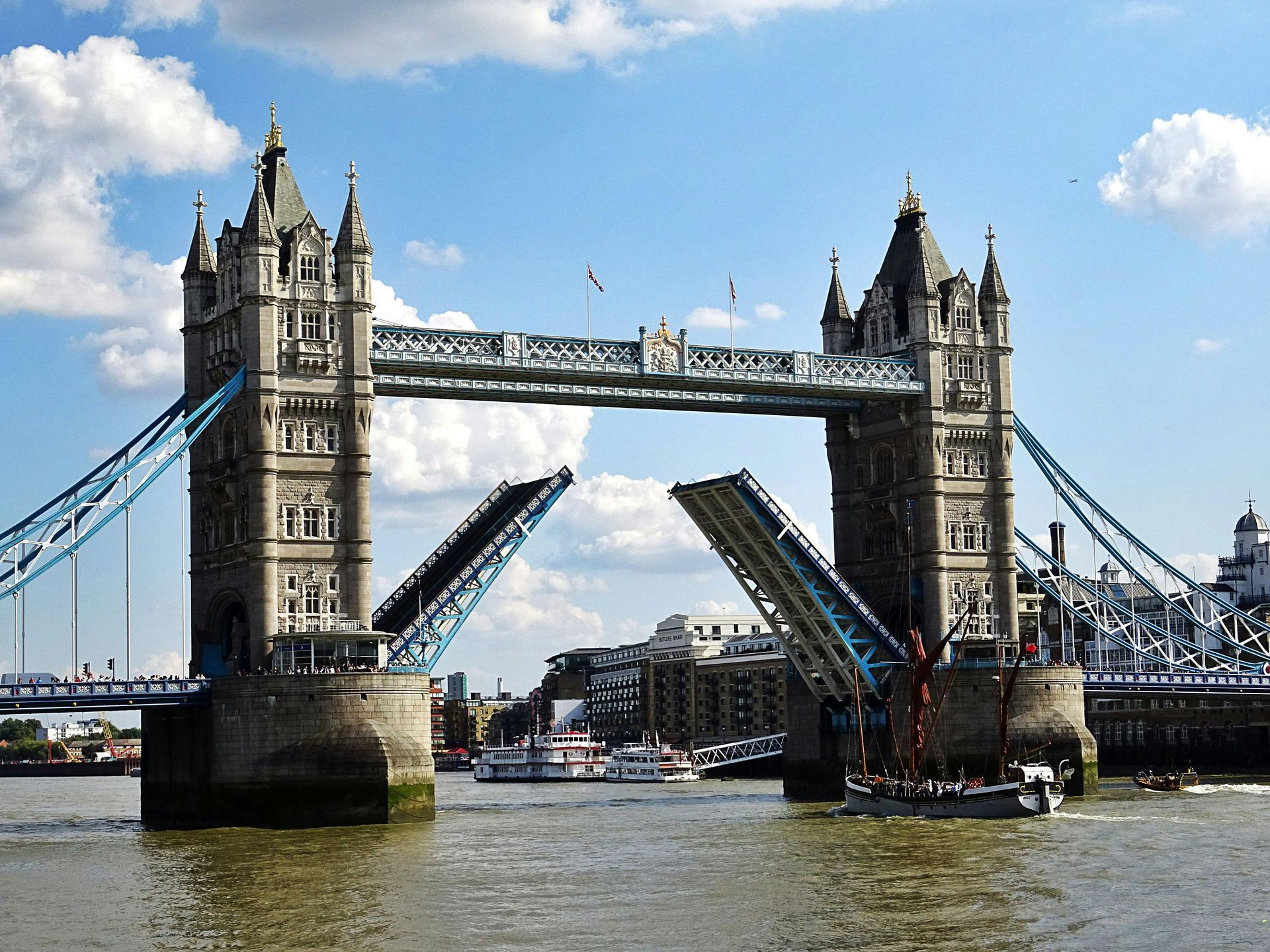 Tower Bridge over the Thames River in London, England, raised to allow a boat to pass, blue sky.
