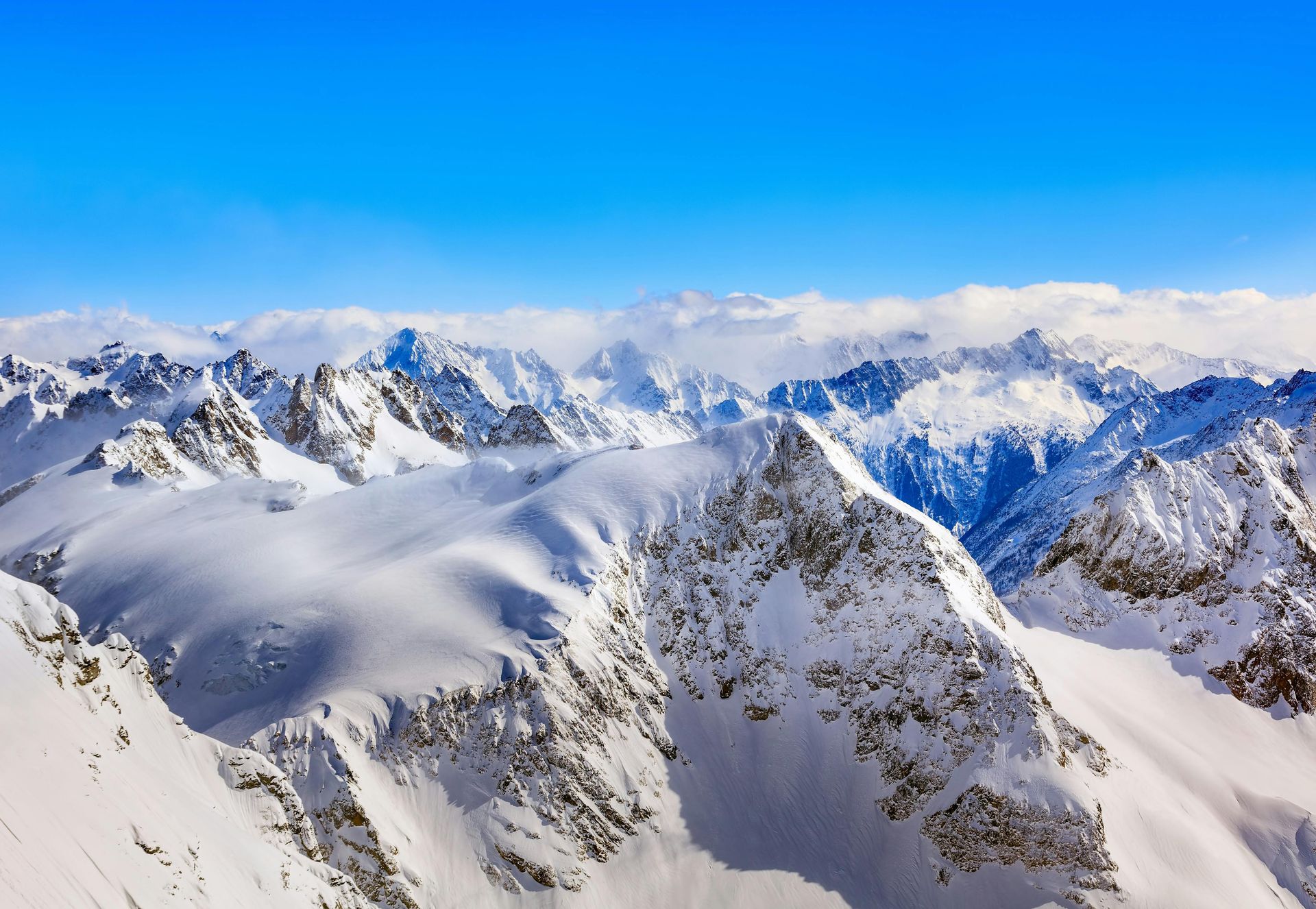 Snow-covered mountain peaks under a clear, bright blue sky. Swiss Alps