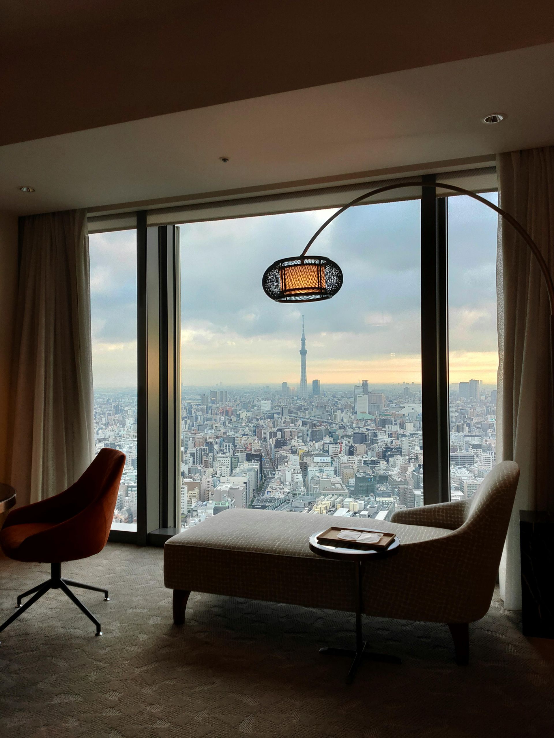 Interior of a dimly lit bar with illuminated wooden surfaces and shelves, and a bartender serving drinks. Tokyo hotel  Mandarin Oriental, Tokyo
