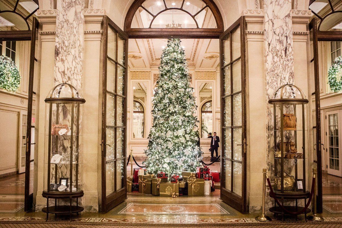 Grand entrance with open doors framing a decorated Christmas tree and gifts.