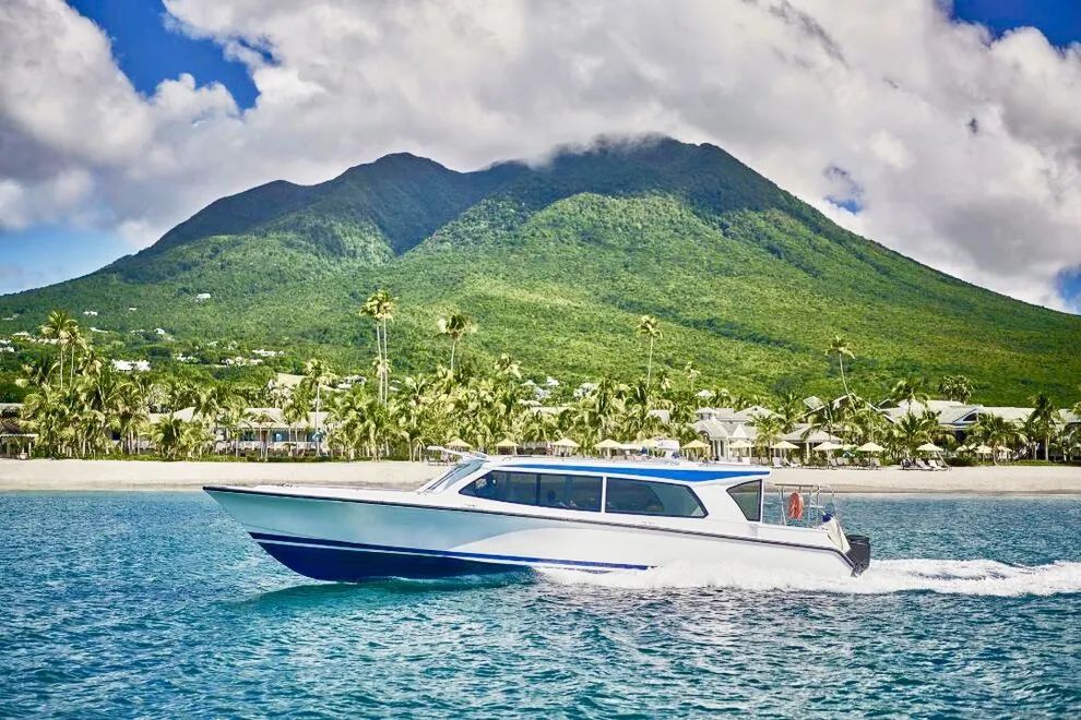 Boat speeds on turquoise water with a lush green mountain in the background.