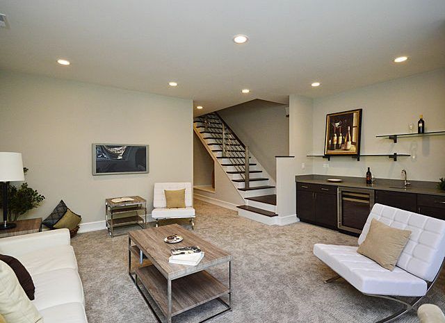 Living room with modern furniture and staircase leading up to the main floor