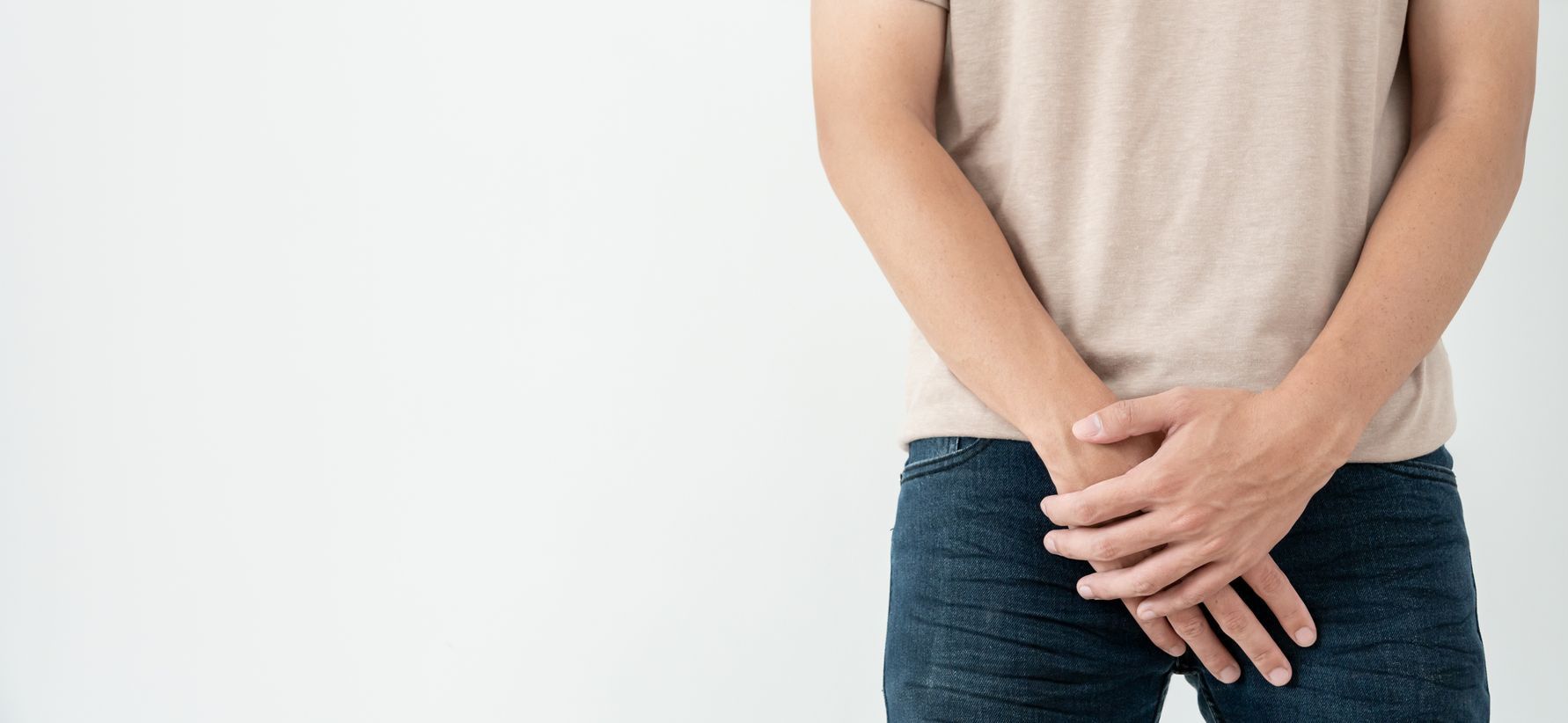 Ein Mann hält seine Hände über seine Hose.