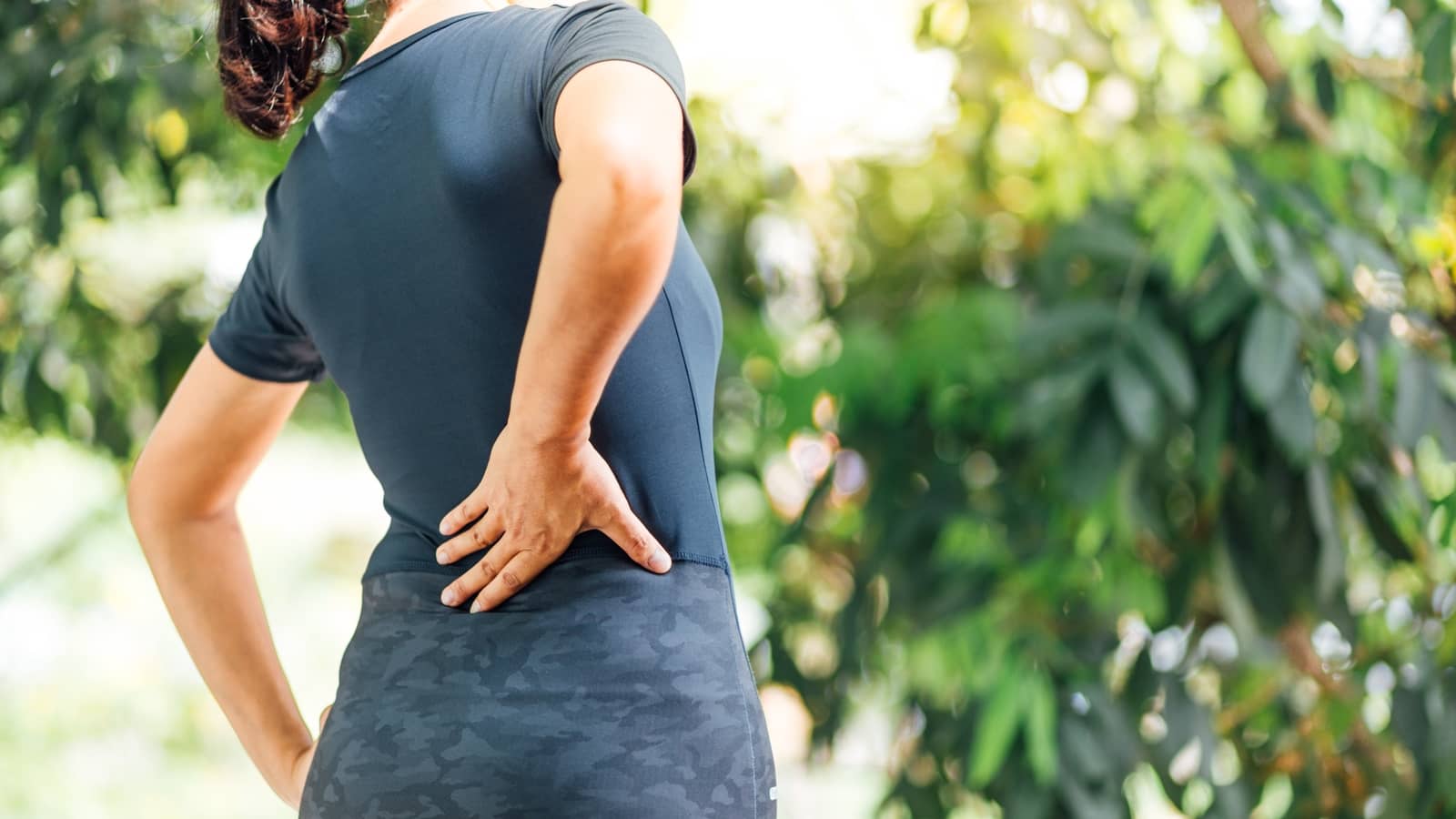 Woman experiencing lower back pain during an exercise outdoors