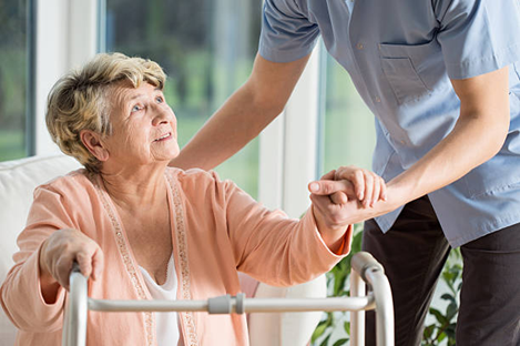 Elderly woman with a walking frame being assisted by an aged care nurse