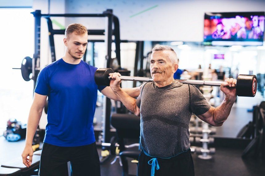 exercise physiologist with elderly man performing strength training
