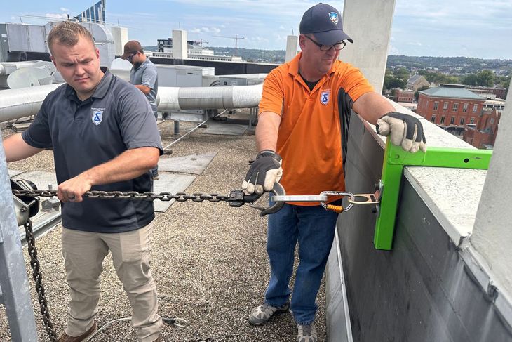 Two men are working on the roof of a building.