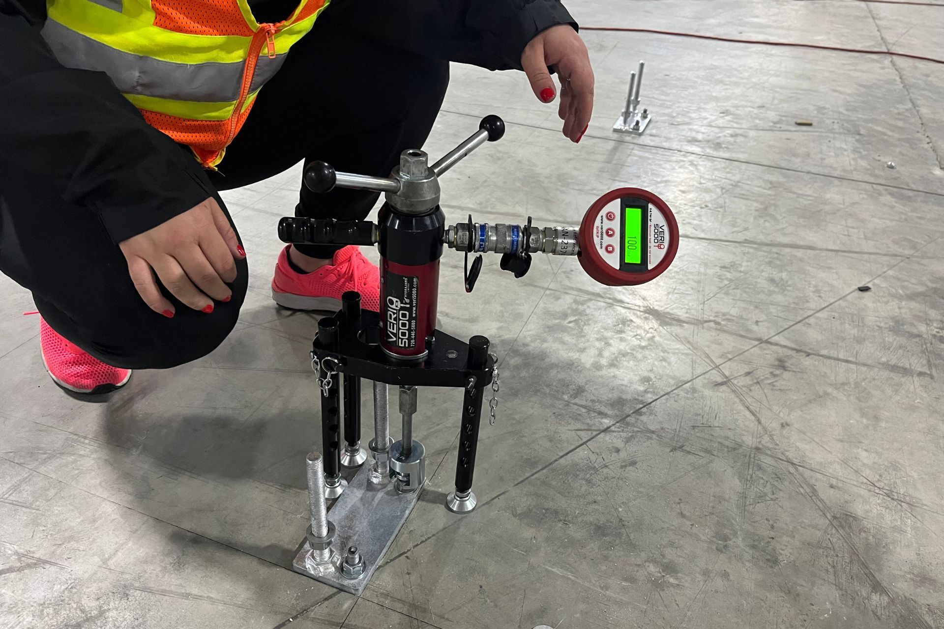 A woman is kneeling down next to a machine on the floor.