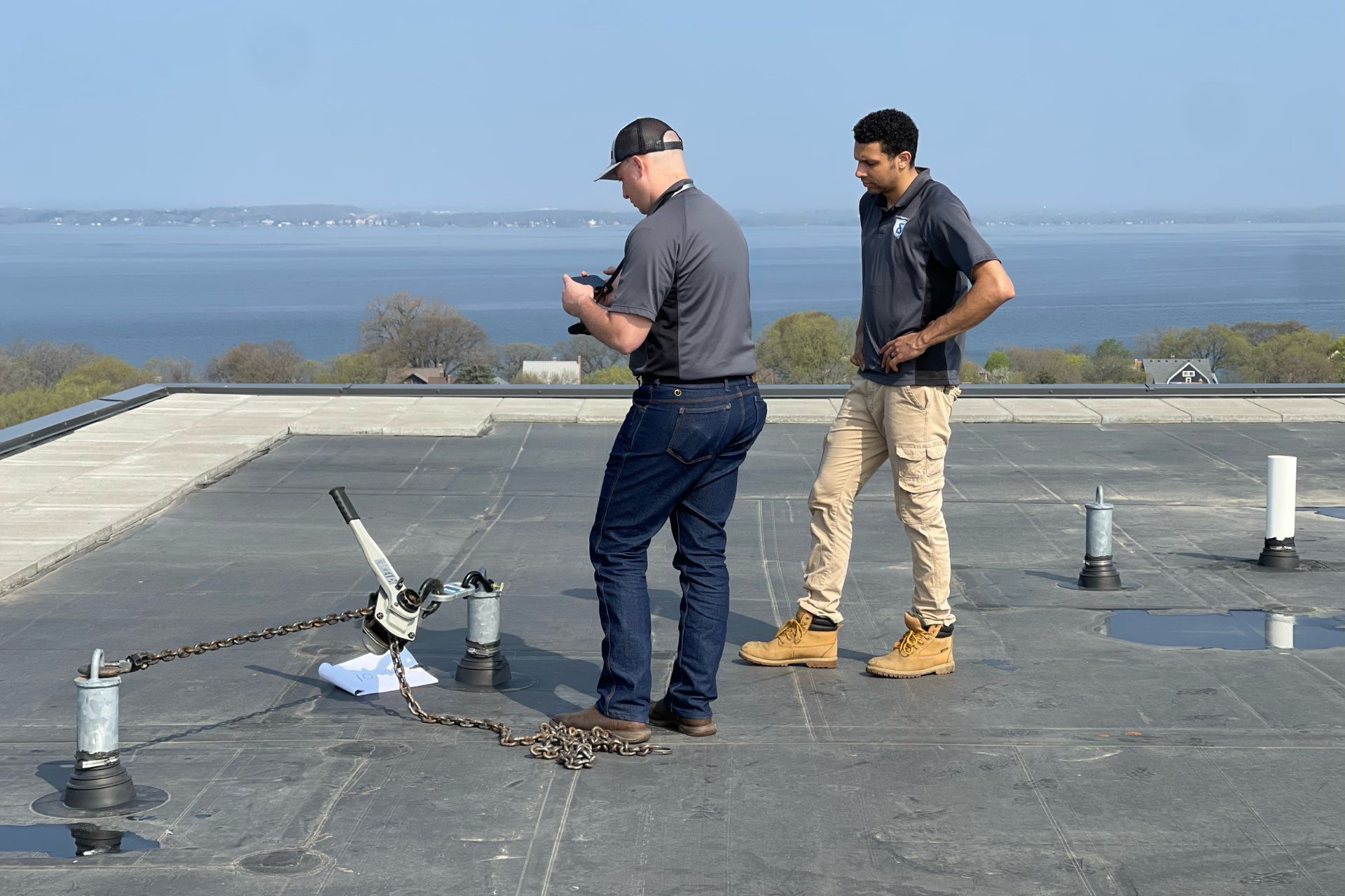 Two men are standing on top of a roof looking at something.