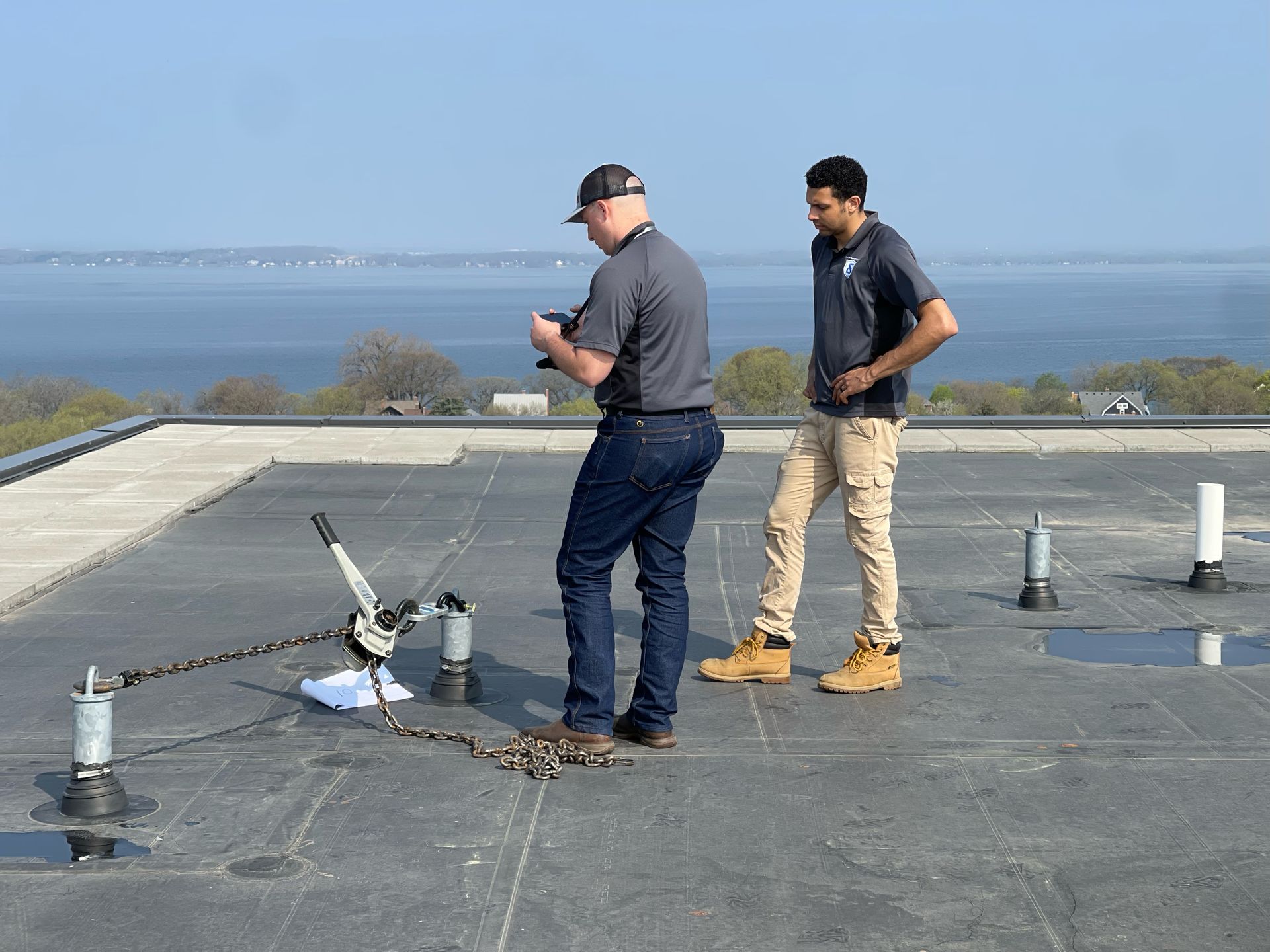 Two men are standing on top of a roof looking at something.