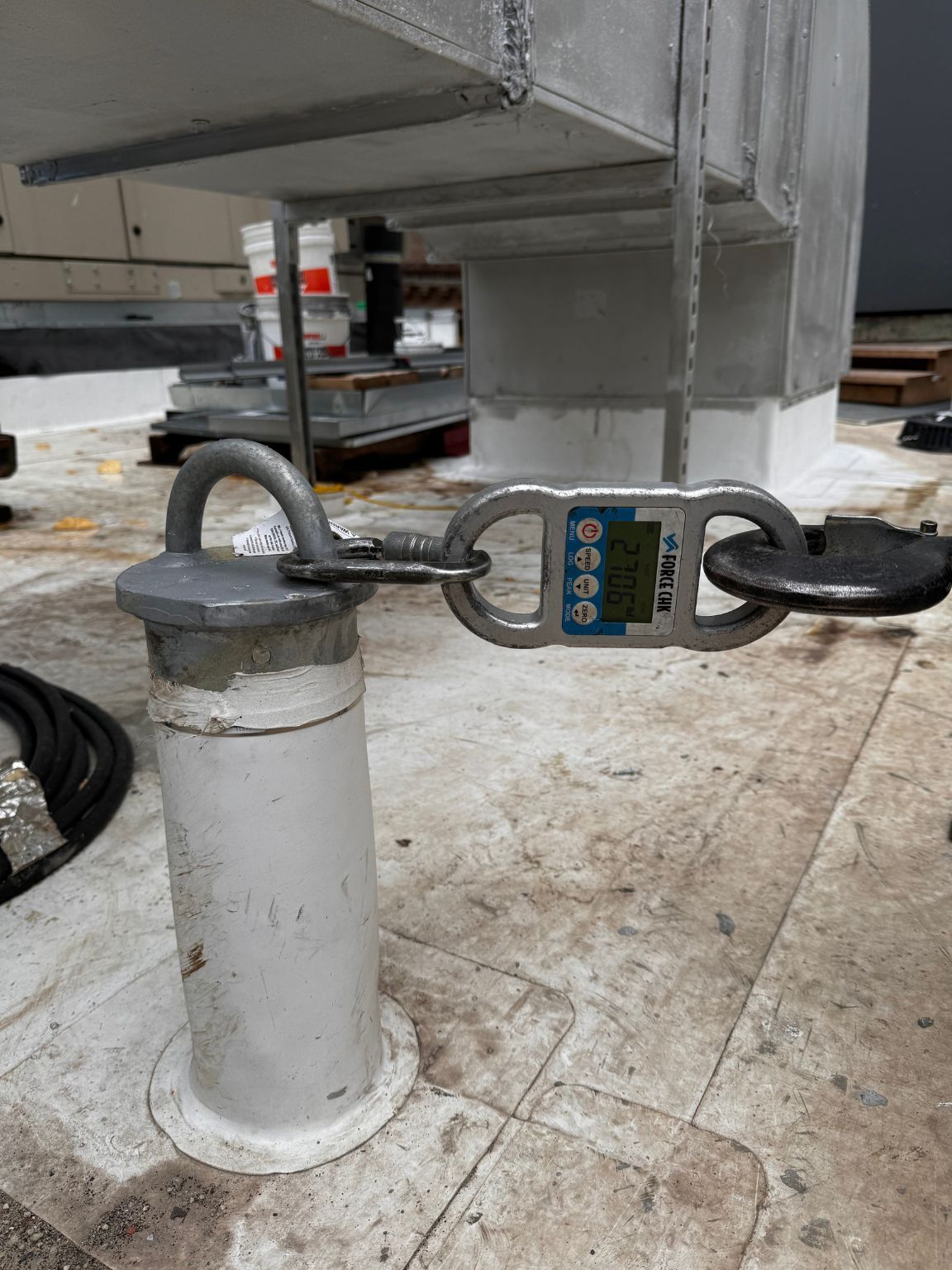 A close up of a stainless steel anchor with a digital scale attached to it.