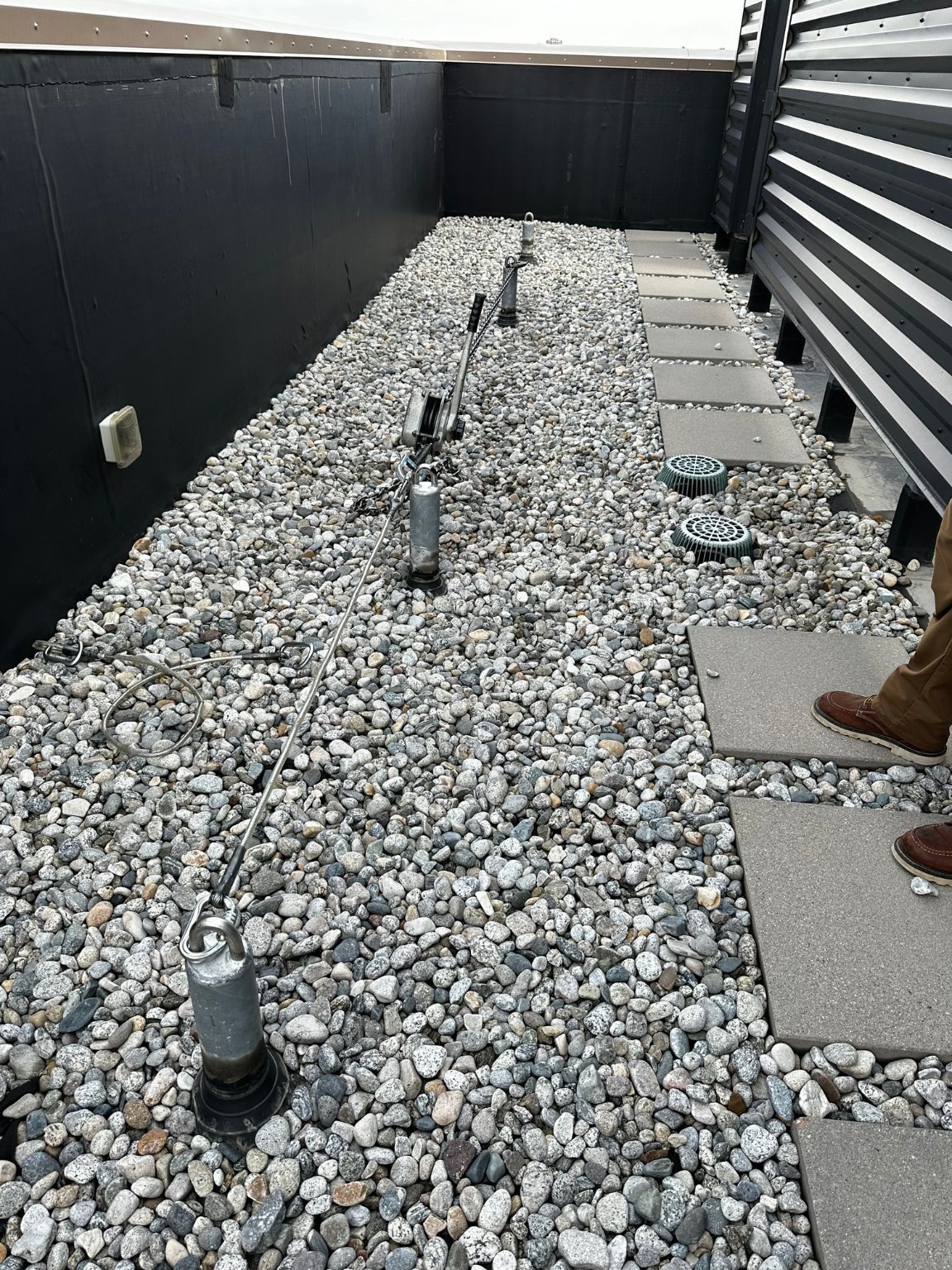 A person is standing on a gravel covered roof.