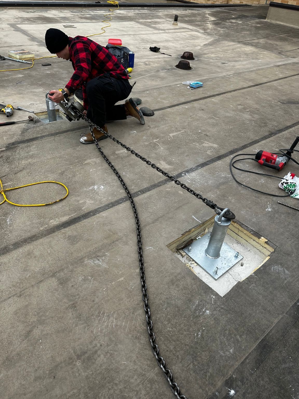 A man is kneeling down on the ground working on a roof.