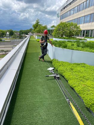 A man is walking on a rooftop with a rope attached to it.