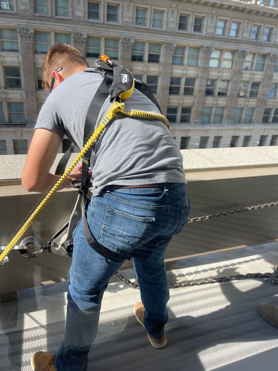 A man wearing a safety harness is standing on a balcony.