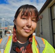 A woman wearing a yellow vest is smiling for the camera