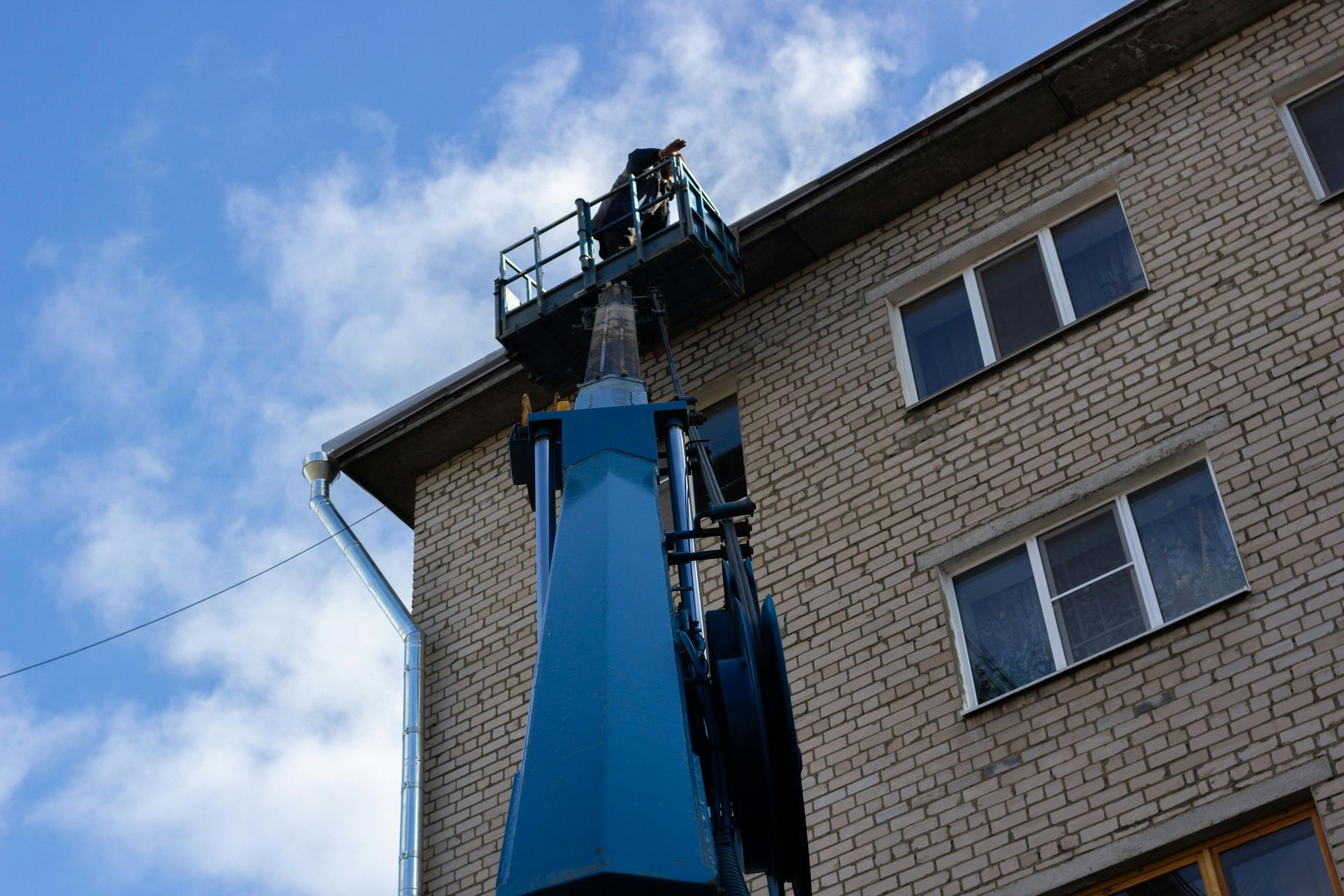 A man is working on the roof of a building with a crane.