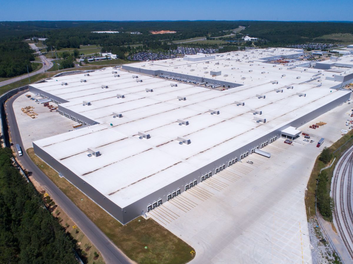 Overhead view of a gray industrial roof with several cylindrical ventilation units and various rectangular structures.