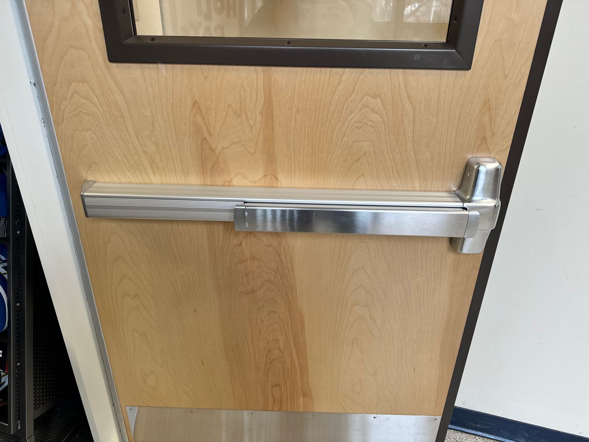 an exit door with a stainless steel push bar panic device.
