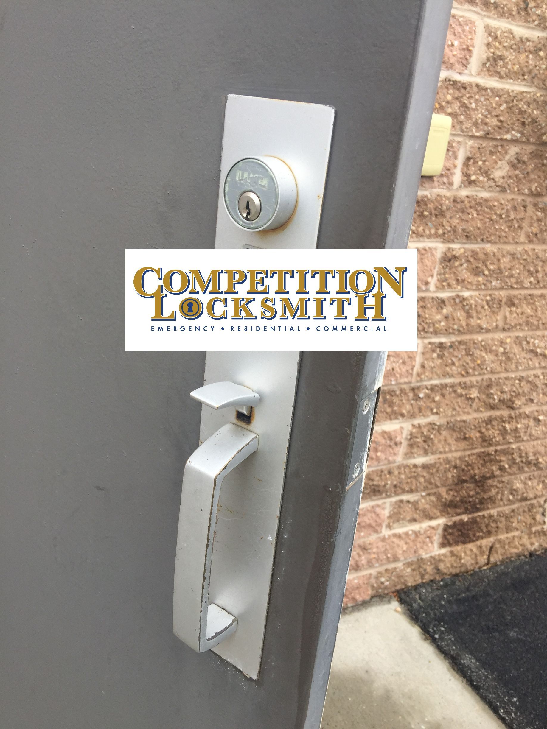 a close up of a exterior warehouse door with a competition locksmith logo on it .