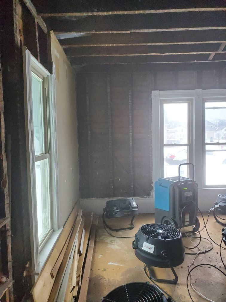 A room with a lot of industrial fans on the floor and a window.