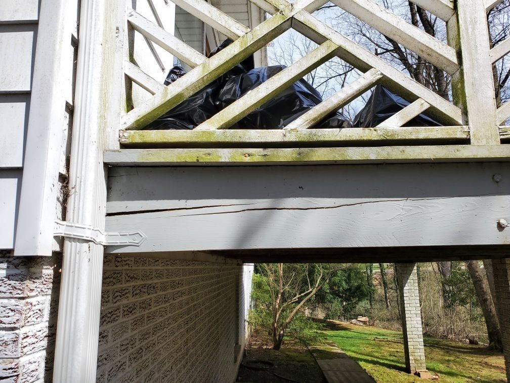 A white house with a wooden deck underneath it.