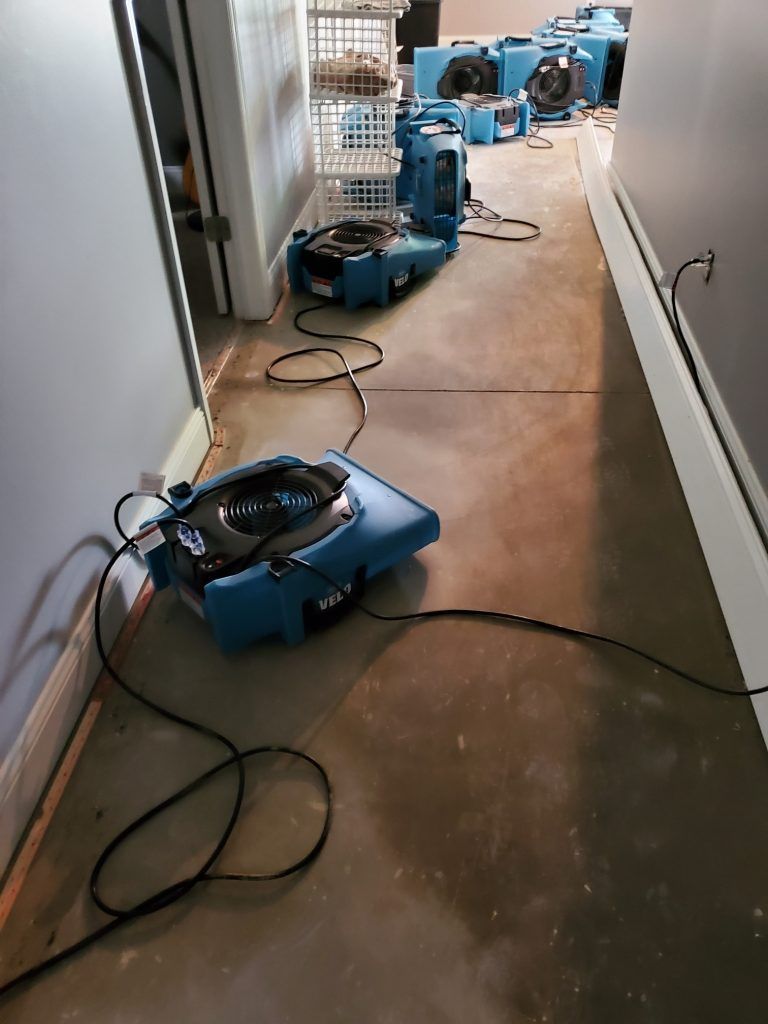 A hallway with an industrial dryer on the floor.