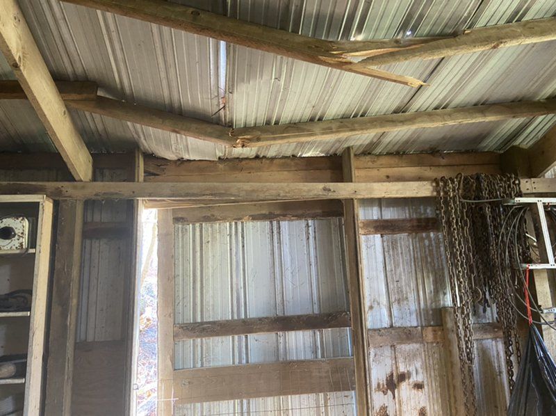 The inside of a barn with wooden beams and a metal roof.
