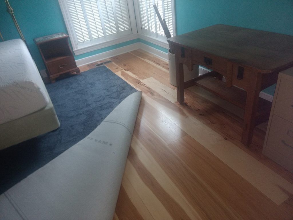 A room with hardwood floors, a wooden table, blue rug and blue walls.