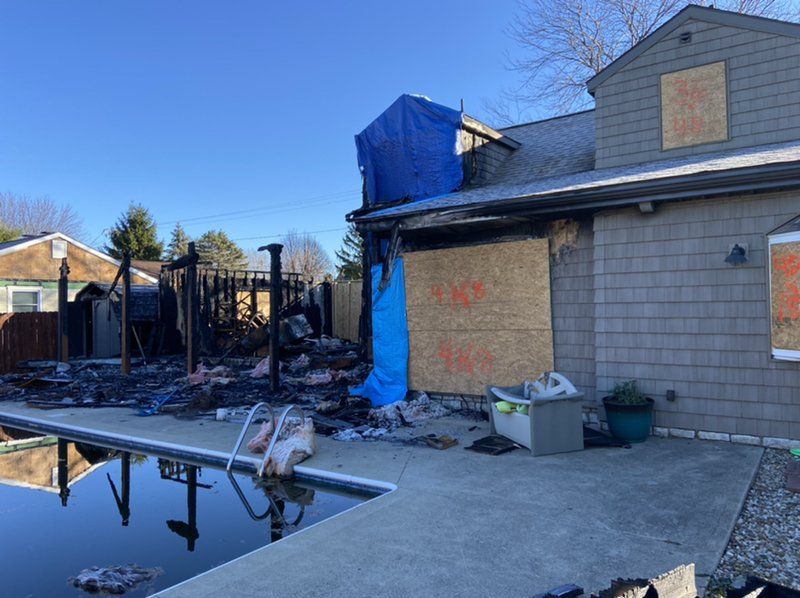 A house that has been damaged by a fire with a pool in front of it.