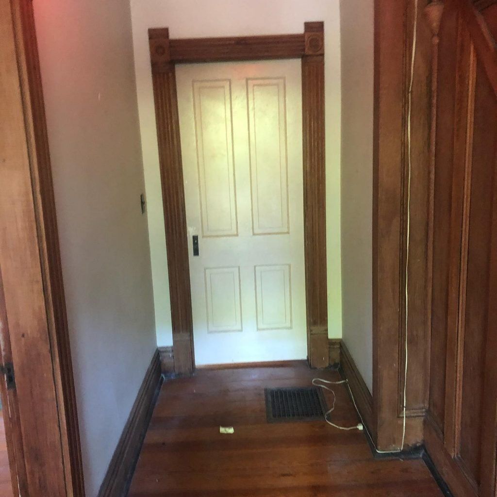 A hallway with a white door and wooden trim.