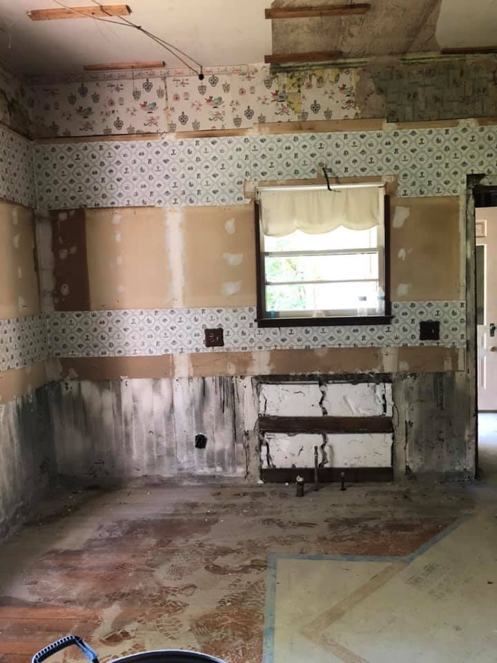 An empty room being remodeled with a window and a bucket on the floor.
