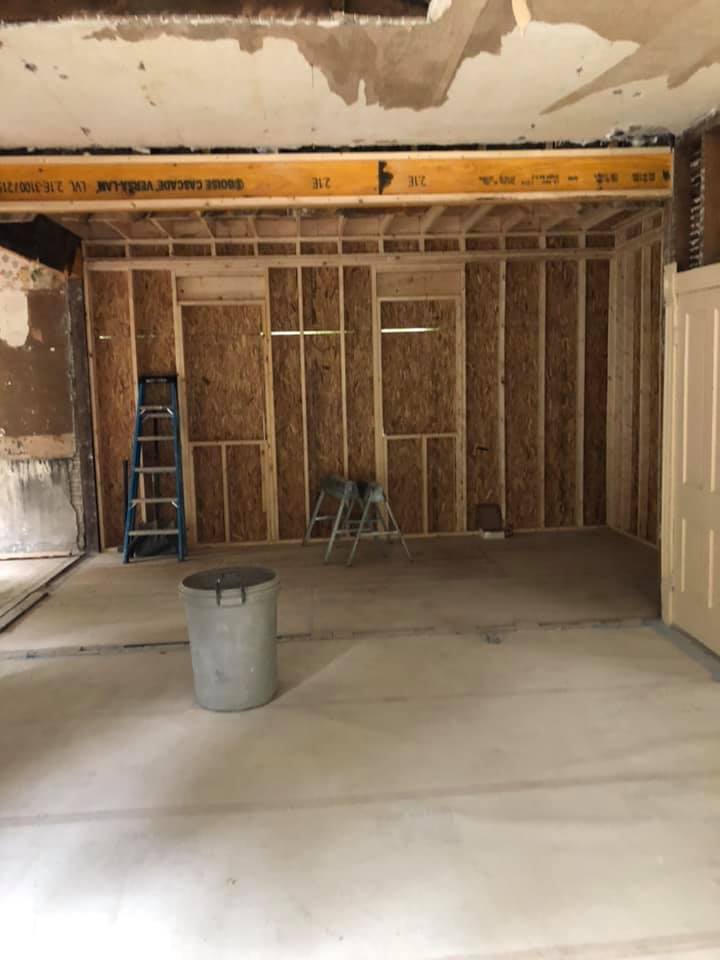 An empty room with a bucket and a ladder inside. 