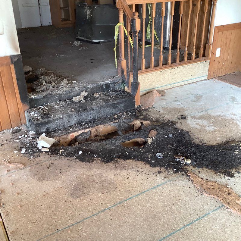 A room with a staircase damaged by fire.