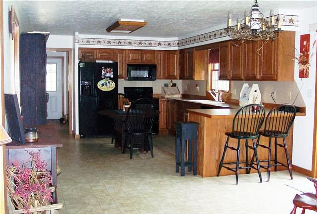 A kitchen with wooden cabinets and a black refrigerator.