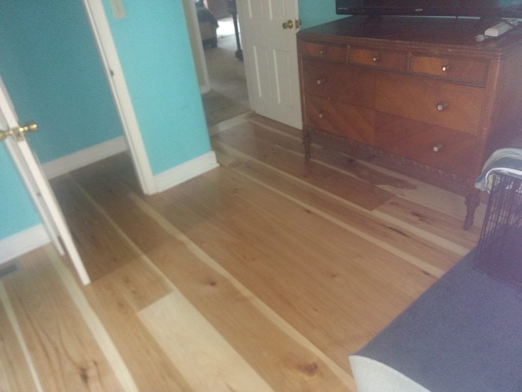 A living room with green walls, hardwood floors, and a dresser.