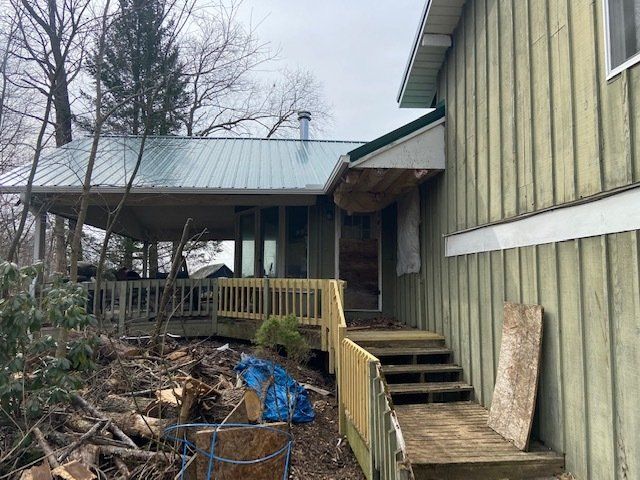 A green house with a metal roof and a wooden deck.