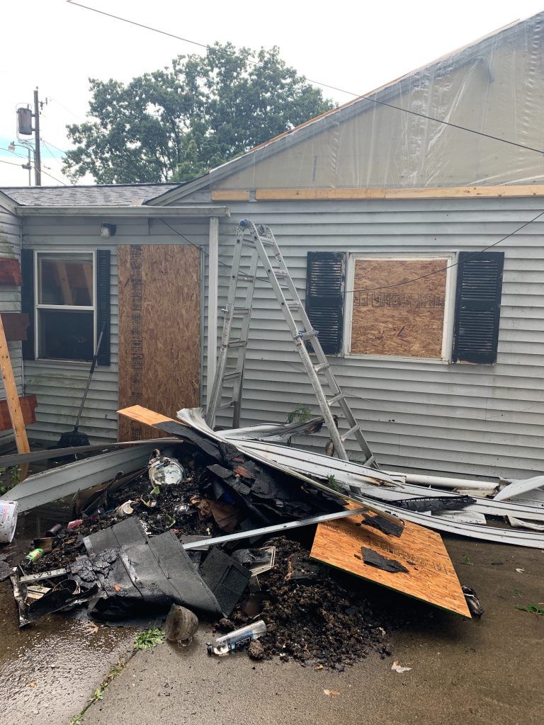 A house that has been damaged by a fire with a ladder in front of it.