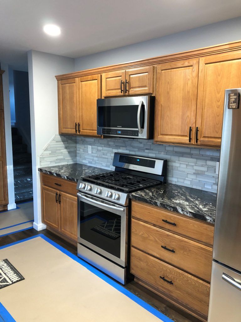 A kitchen with wooden cabinets, stainless steel appliances, and granite counter tops.