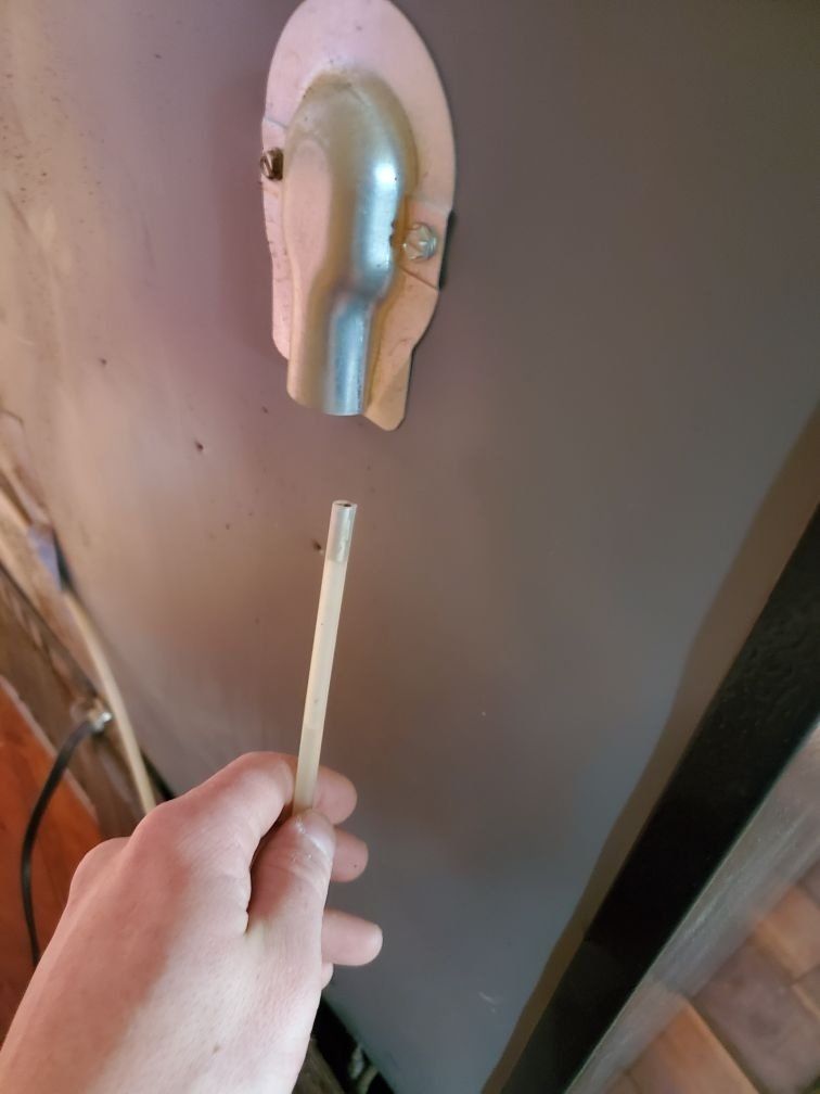 A person is holding a piece of wood in front of a wall.