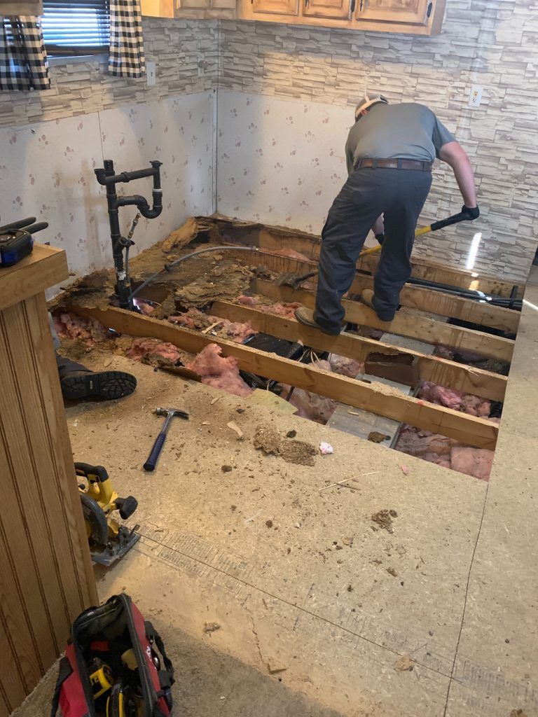 A man is working on the floor of a kitchen.