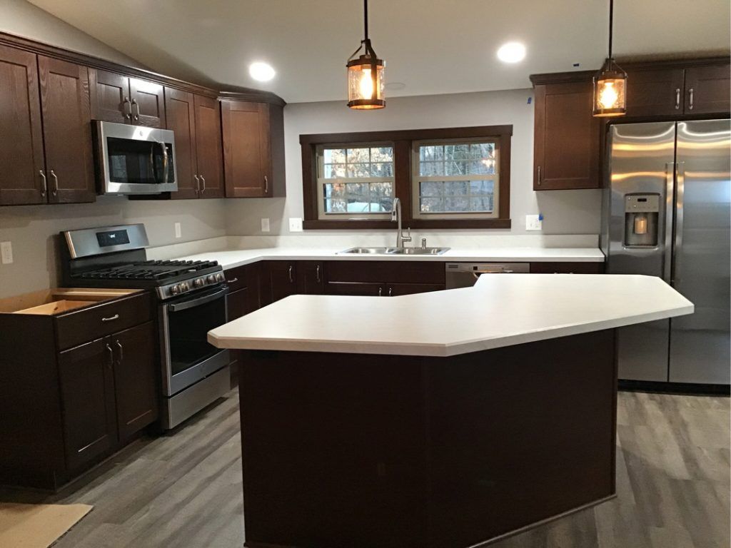 The fully restored kitchen with an island and white countertop finish.