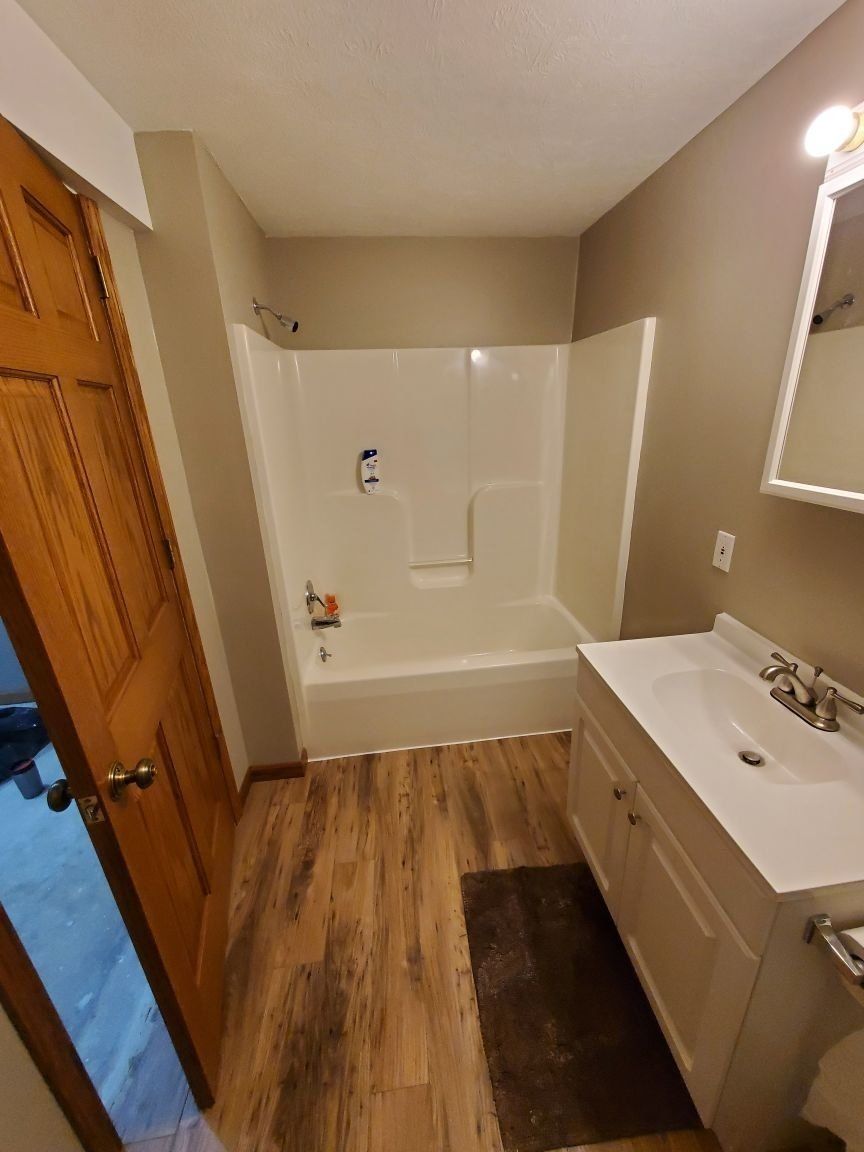 A bathroom with a sink , tub , shower and mirror.