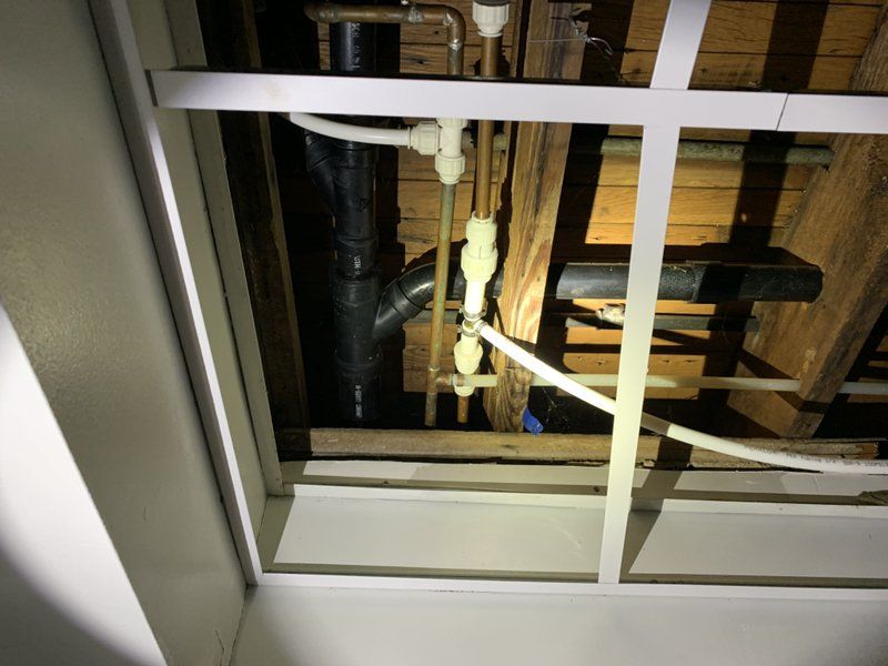 Looking up at the ceiling of a building with pipes and wires.